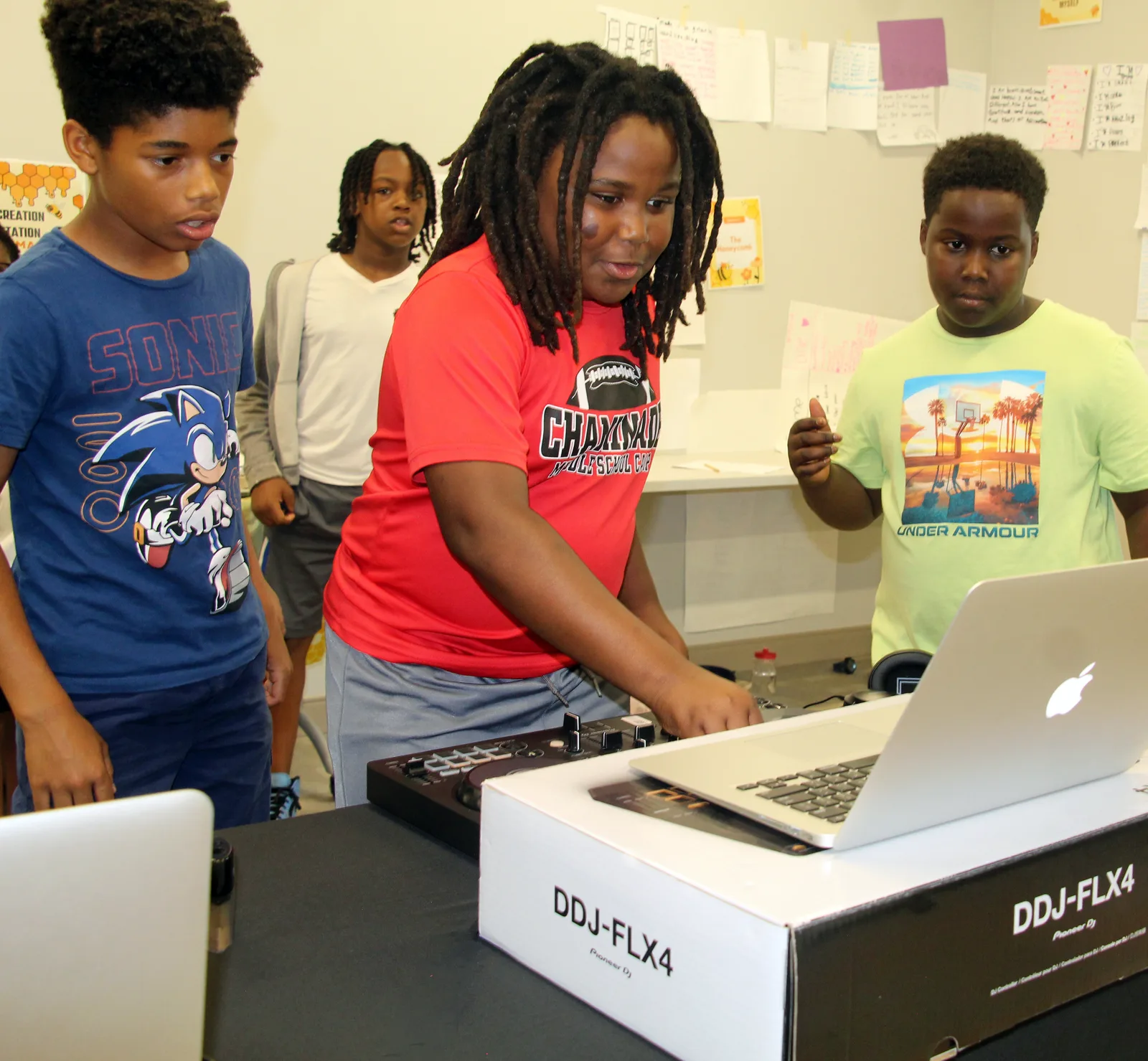Young people learning together as a student practices on a DJ controller