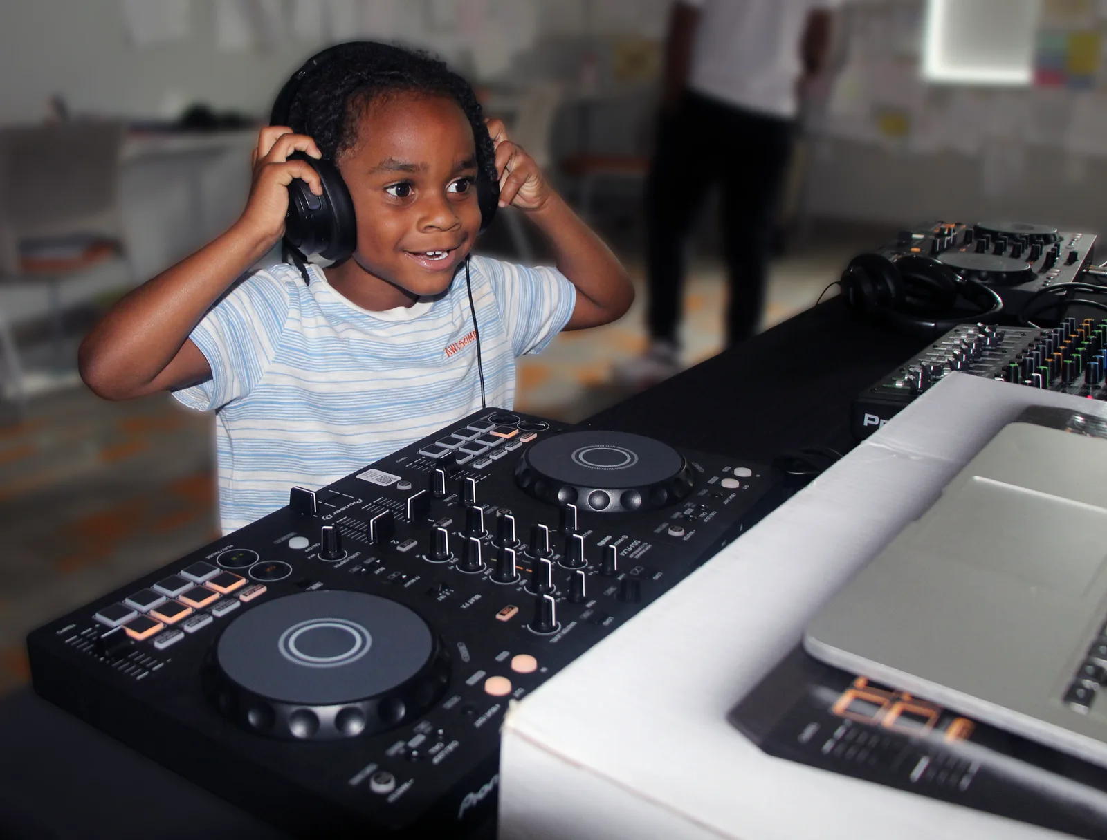 A young student using headphones at a DJ controller during a Future of Music class